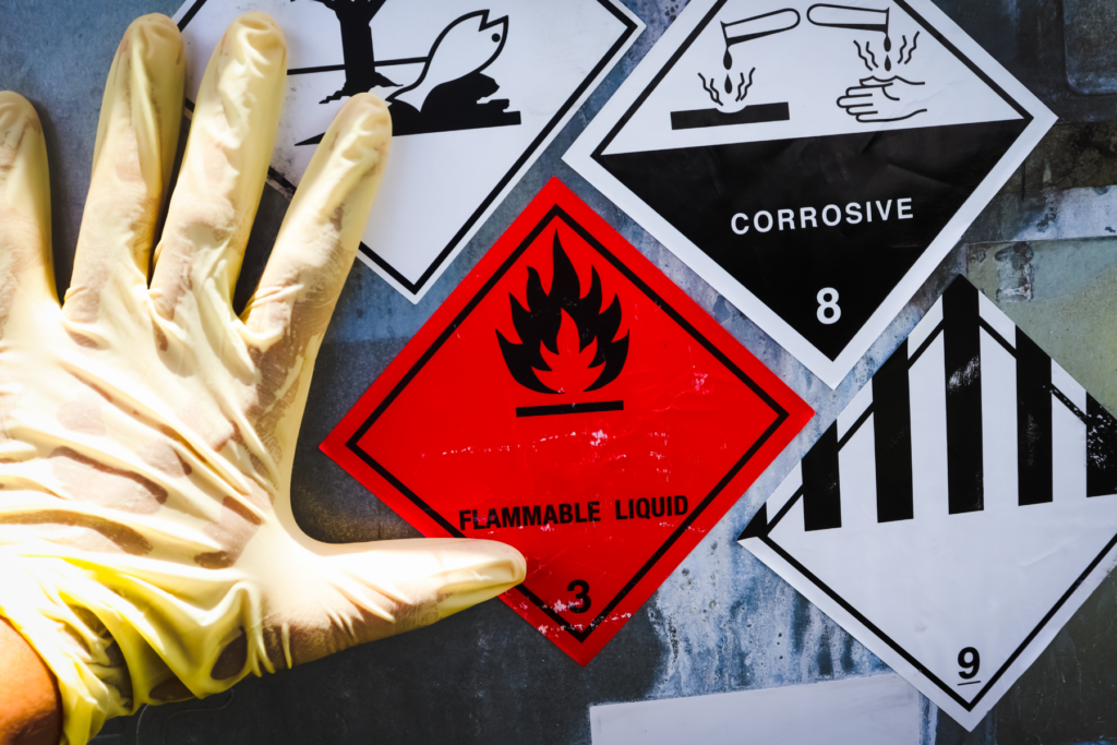 Close up of hand with rubber glove on and hazard signs