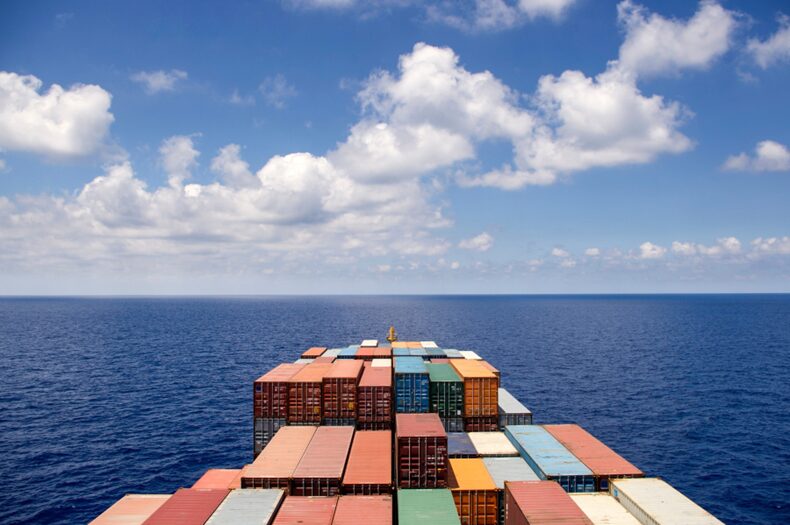 A close up shot of some stacked cargo containers on a ship sailing through the sea