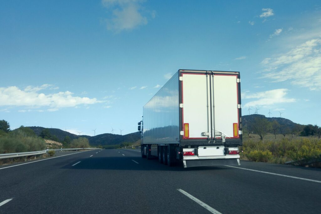 A white truck with semi-trailer driving along the highway
