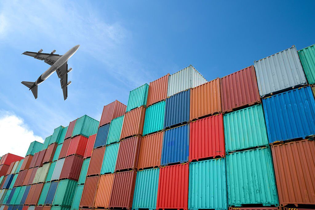 an airplane flying over cargo containers.